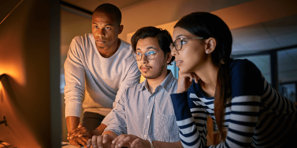 A small group of data scientists and modelers gathered around a computer 