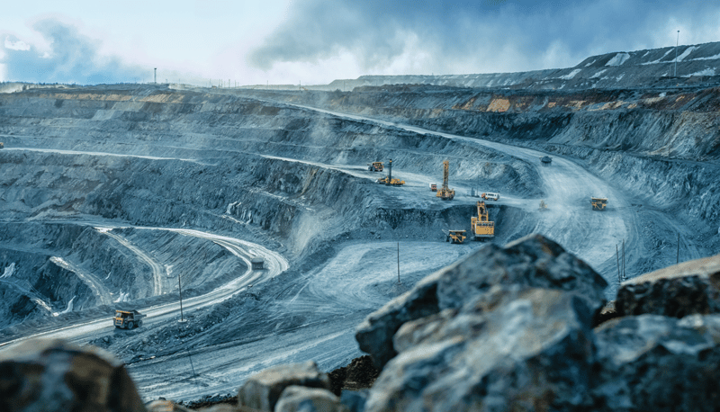 Mine worker inspecting ore rocks as they move along a conveyor belt