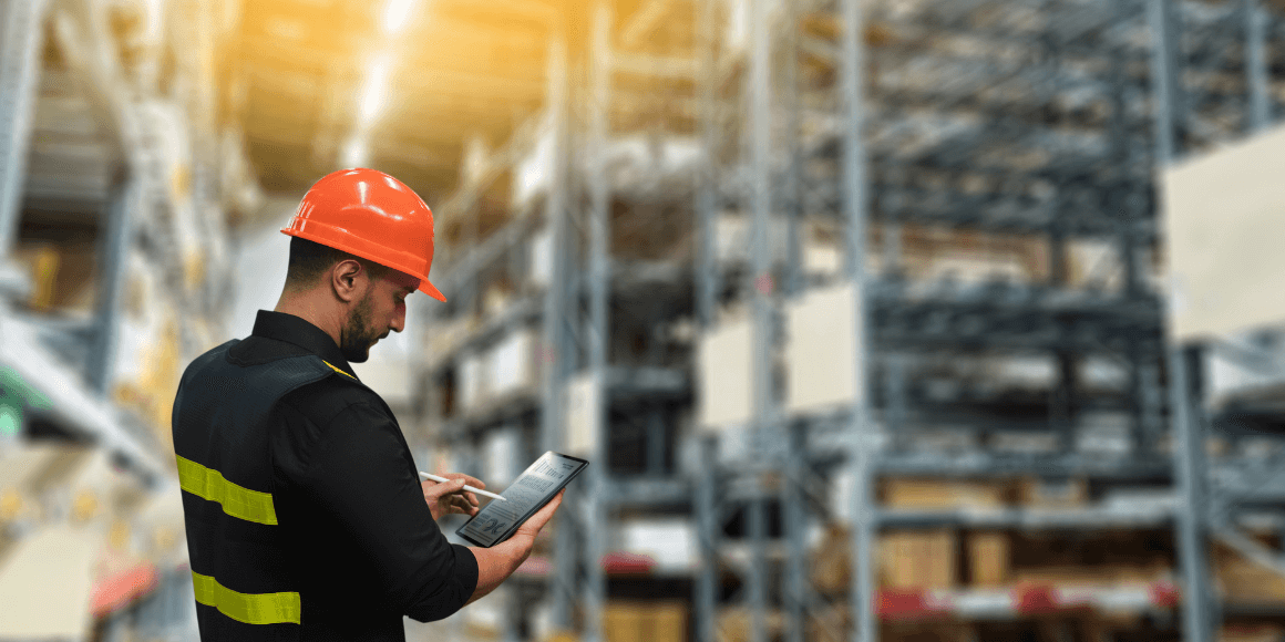 Supply chain manager standing in a warehouse checking inventory on a tablet