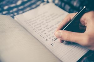 Supply chain planner creating a checklist in their notebook